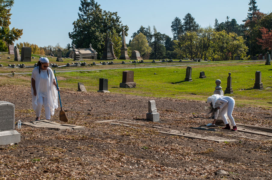 Shy Pacheco Hamilton and student sweeping the cemetery, 2017